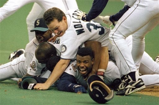 Seattle Mariners Ken Griffey Jr. smiles from beneath a pile of teammates who mobbed him after he scored the winning run in the bottom of the 11th inning of a baseball game against the New York Yankees in Seattle