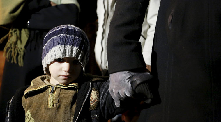 A Syrian boy waits with his family who say they have received permission from the Syrian government to leave the besieged town as they depart after an aid convoy entered Madaya Syria