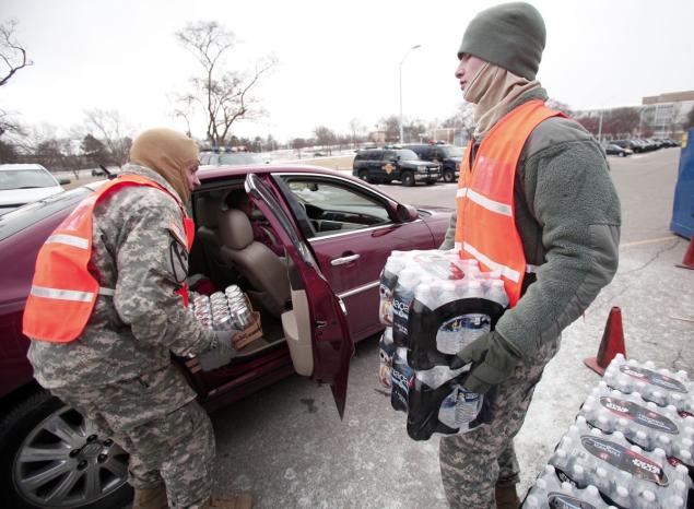 Soldiers from the Michigan Army National Guard hand out bottled water at a Flint fire station Sunday. Residents have called on the state to help them with their water bills during the city's water crisis