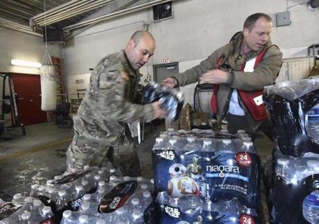 Michigan Nation Guard Sgt. Steve Kiger left stacked cases of drinking water with Red Cross volunteer Franklin Dickerson