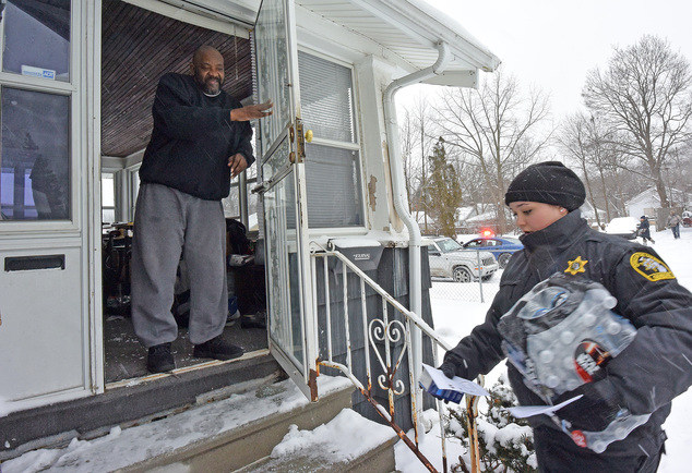 Samuel Smith is happy to receive a case of bottled water and a new water filter at his home on Mallery St. in Flint Mich. as volunteers accompanied by Mich