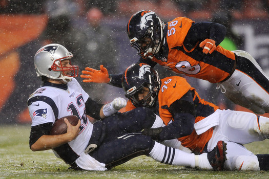 Quarterback Tom Brady #12 of the New England Patriots is sacked by defensive end Vance Walker #96 of the Denver Broncos and hit by outside linebacker Von Miller #58 of the Denver Broncos in the third quarter at Sports Authority Field at Mile High