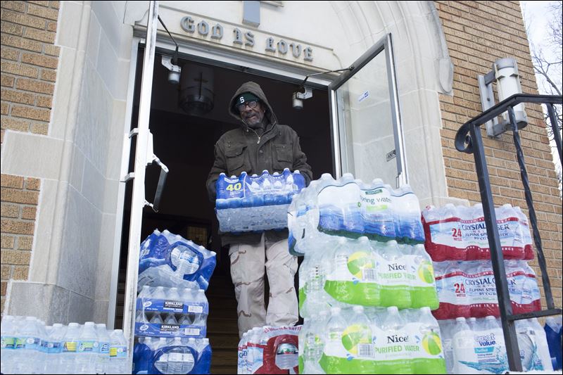 Maurice Rice organizes cases of water at the Joy Tabernacle Church on Monday in Flint Mich