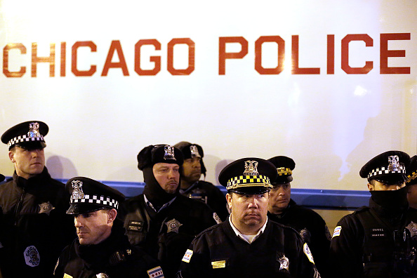 CHICAGO IL- DECEMBER 18: Chicago police officers surround a police vehicle as they watch demonstrators protesting the fatal police shooting of Laquan Mc Donald