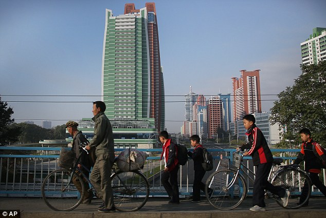 North Koreans walk past a new showcase development in the capital Pyongyang