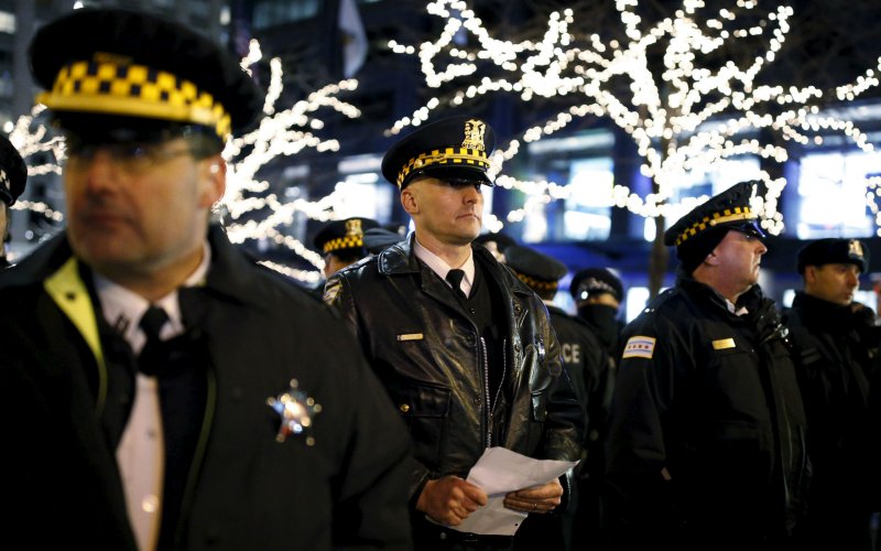 Police officers watch protesters during a demonstration in reaction to the fatal shooting of Laquan Mc Donald in Chicago Illinois