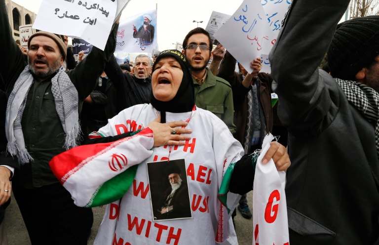 AFP  Iranian protesters hold signs and shout slogans during a demonstration in Tehran