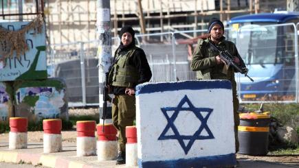 Israeli soldiers stand guard at a West Bank checkpoint