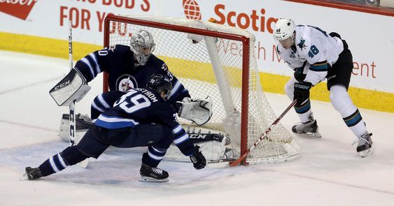 Connor Hellebuyck and teammate Toby Enstrom just get their sticks in the way of a wraparound attempt by San Jose Sharks Tomas Hertl during the first period of an NHL hockey game Tuesday Jan. 12 2016 in Wi