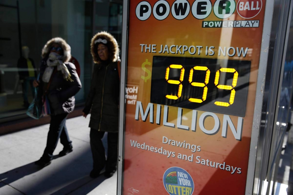 People walk past a sign advertising the Powerball lottery in New York Monday Jan. 11 2016
