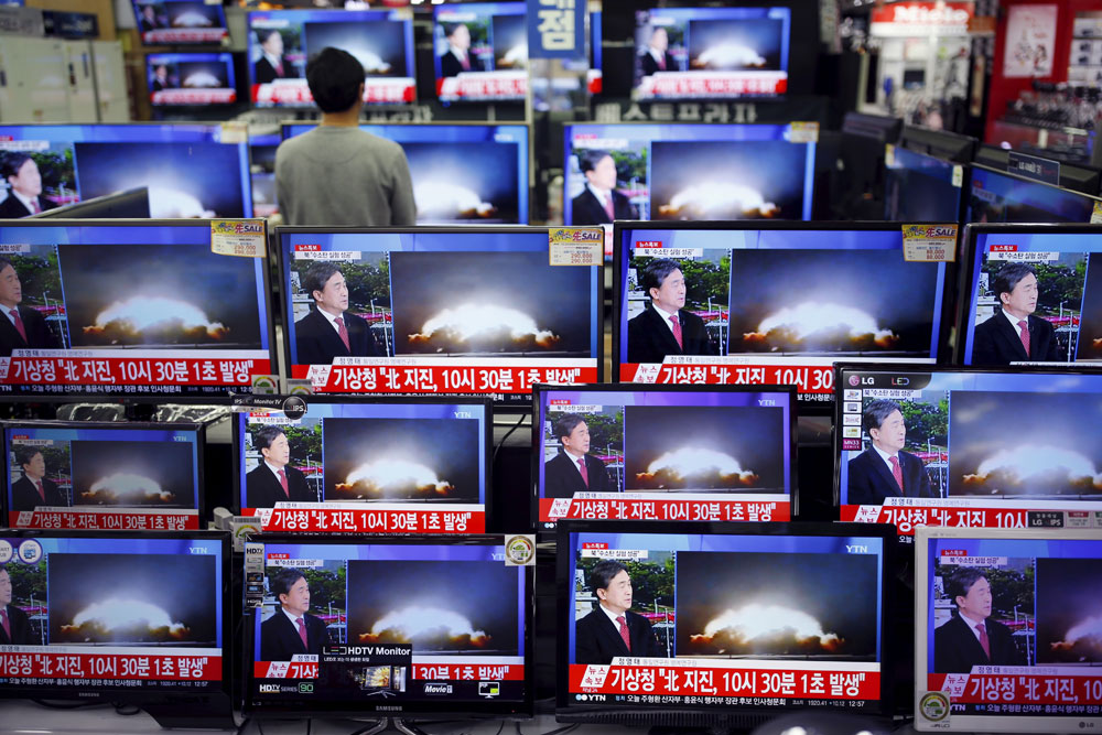 A sales assistant watches TV sets broadcasting a news report on North Korea's nuclear test in Seoul