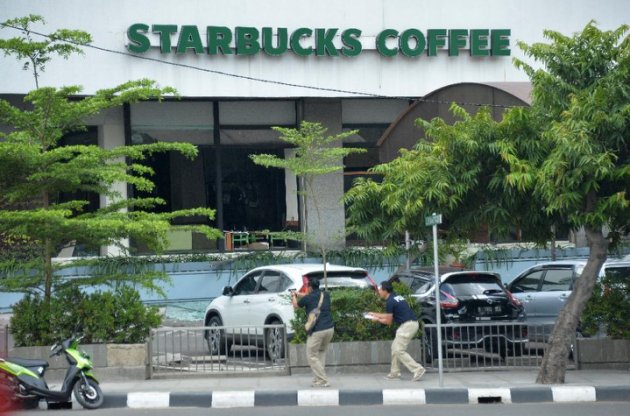 Plainclothes police aim their handguns towards suspects outside a cafe after a series of blasts hit