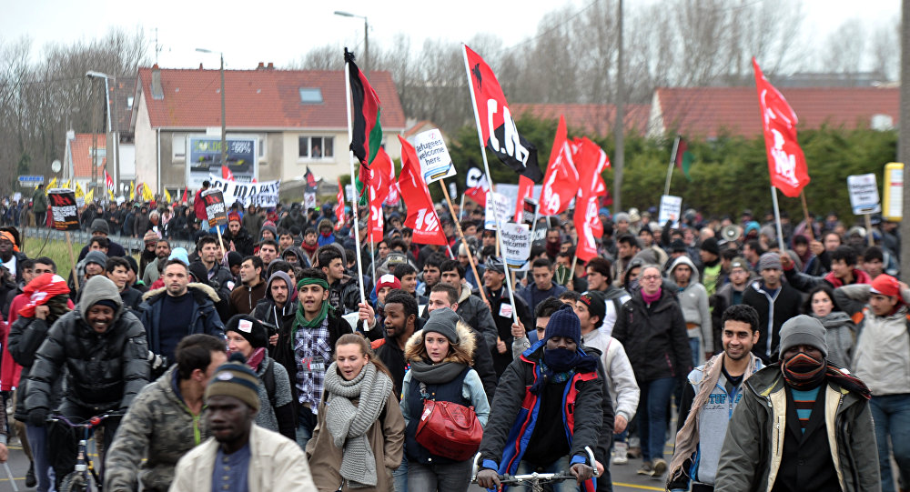 People take part in a demonstration to support migrants who live in a migrant camp on the edge of town nicknamed the Jungle