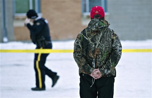 A man holds a rosary as police investigate the scene of a shooting at the community school in La Loche Saskatchewan on Saturday Jan. 23 2016. The shooting took place on Friday. Saturday Jan. 23 2016