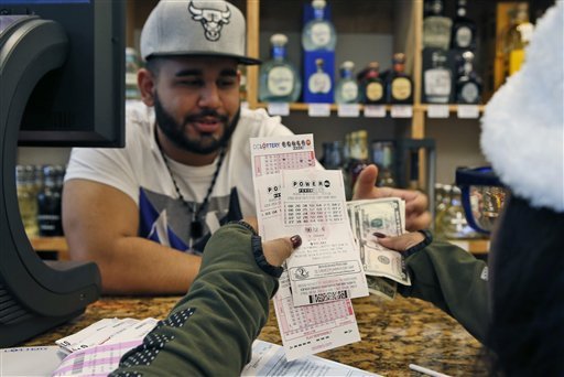 Samir Akhter the owner of Penn Branch Liquor exchanges money for Powerball tickets Saturday Jan. 9 2016 in Washington. Officials say it's increasingly likely that someone will win the 0 million Powerball jackpot which grew by 0 million just hours