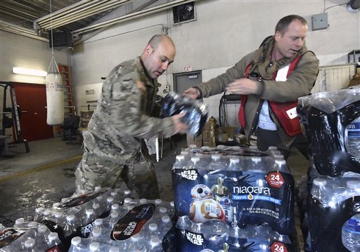 Michigan Nation Guard Sgt. Steve Kiger left of Harrison Mich. stacks cases of drinking water with Red Cross volunteer Franklin Dickerson of Pleasant Ridge Wednesday Jan 13 2016 in Flint Mich. Members of the Michigan National Guard began arriving