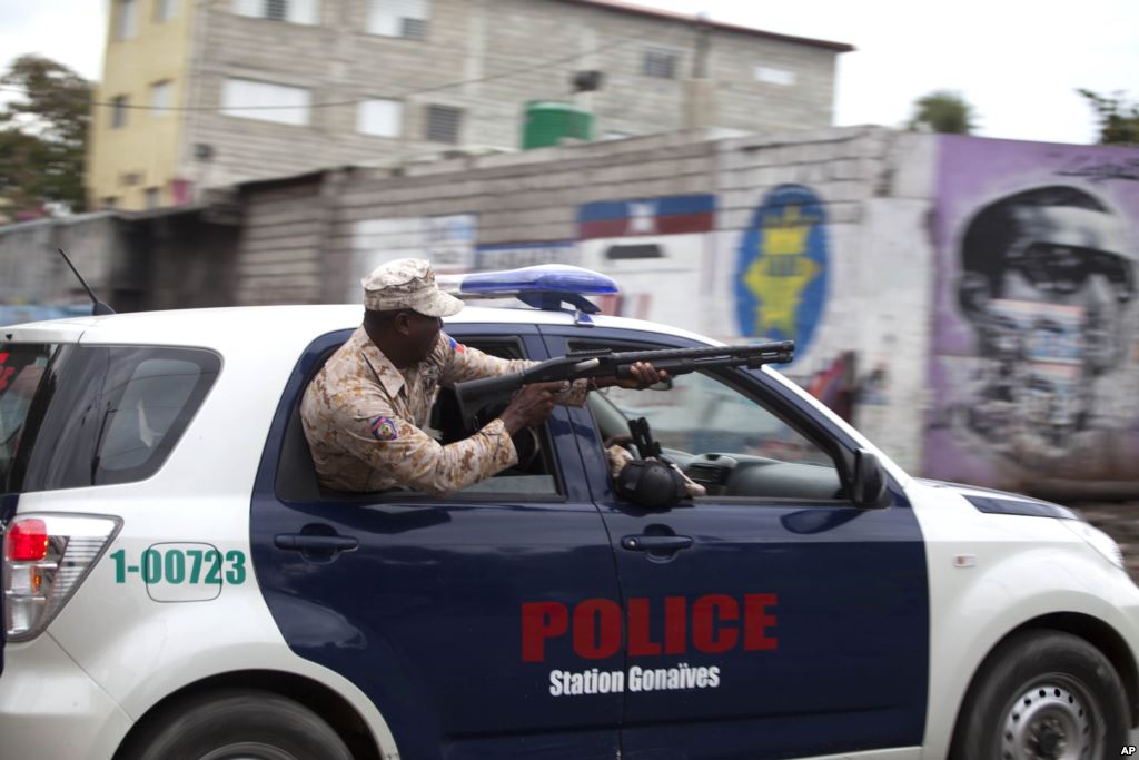 A Haitian national police officer fires birdshot at demonstrators during a street protest after it was announced that the Jan. 24 runoff election had been postponed in Port-au-Prince Jan. 22 2016