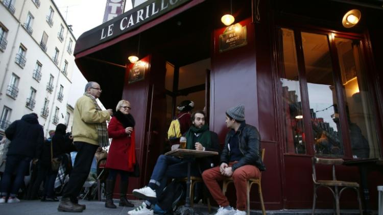 People sit on the terrace of the Carillon cafe one of sites of the November 13 terror attacks in Paris