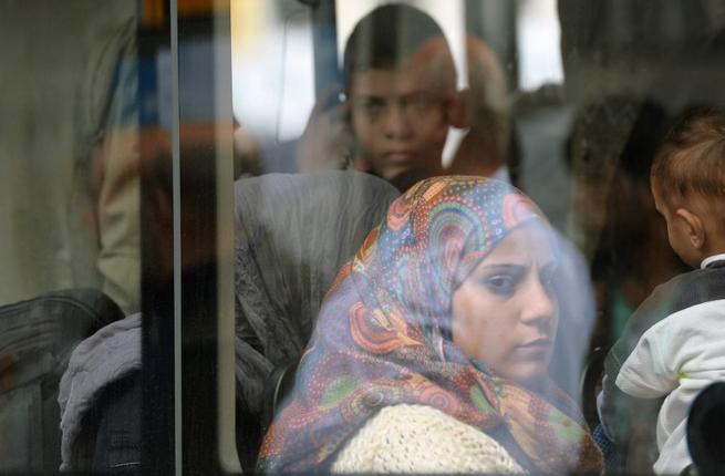 Refugees sit in a bus after they arrive at the main train station in Munich southern Germany