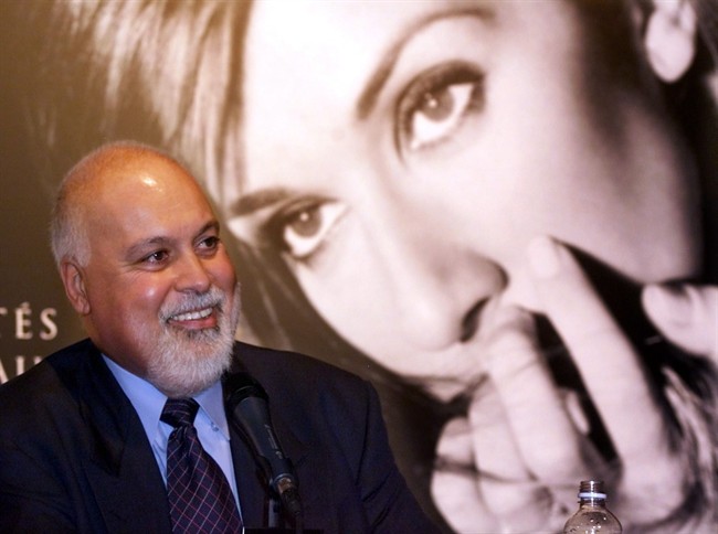 Rene Angelil respnds to a question with a giant photgraph of his wife singer Celine Dion in the background during a news conference in Montreal Wednesday Sept. 8 1999. This is the first public appearance for Angelil since undergoing cancer treatments. A