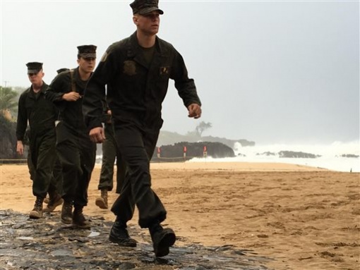 U.S. Marines walk on the beach at Waimea Bay near Haleiwa Hawaii where two military helicopters crashed into the ocean about 2 miles offshore Friday Jan. 15 2016. The helicopters carrying 12 crew members collided off the Hawaiian island of Oahu