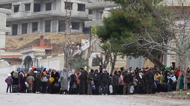 Residents of the besieged rebel-held Syrian town of Madaya wait for a convoy of aid from the Syrian Arab Red Crescent today