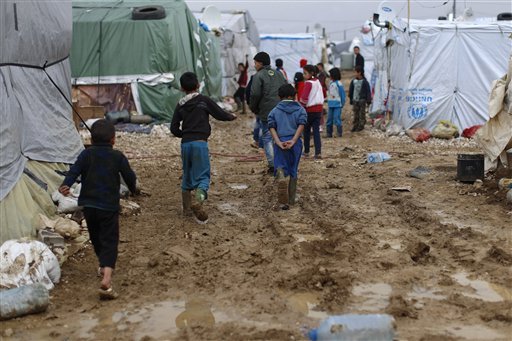 Syrian refugee children walk in mud after a heavy rain at a refugee camp in the town of Hosh Hareem Bekaa valley east Lebanon. In a report published Tuesday Jan. 12 2016 the New York-based rights group