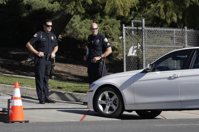 Two Pasadena police officers inspect a vehicle on Colorado Blvd on the route of the Rose Parade in Pasadena Calif. Thursday Dec. 31 2015. Final preparati