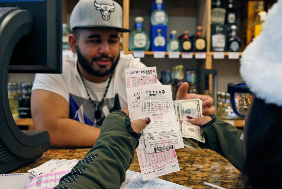 Samir Akhter the owner of Penn Branch Liquor exchanges money for Powerball tickets Saturday Jan. 9 2016 in Washington