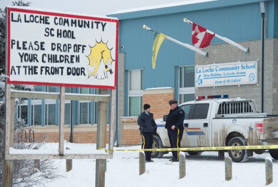 Members of the RCMP stand outside the La Loche Community School in La Loche Sask. Monday Jan. 25 2016. A 17-year-old boy allegedly shot two people at the school last Friday after shooting two brothers to death earlier at a home nearby