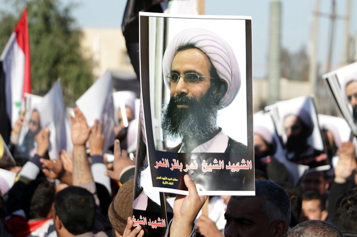 An Iraqi protester holds a poster of Shiite cleric Nimr al-Nimr who was executed in Saudi Arabia during a protest Monday in front of the gate of the Green Zone in Baghdad