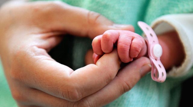 A new born baby takes the finger of his mother after the delivery