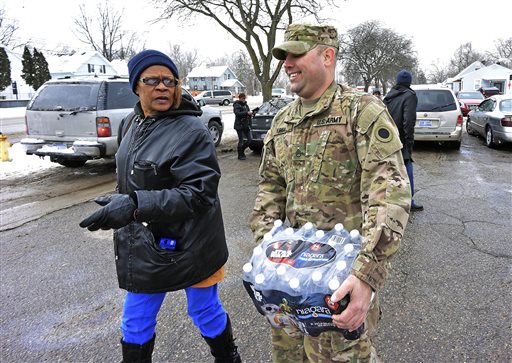 Michigan National Guard Sgt. Steve Kiger of Harrison Mich. carries water for a resident Wednesday Jan 13 2016 in Flint Mich. Members of the Michigan National Guard began arriving in Flint on Wednesday for briefings on the drinking water crisis ahead