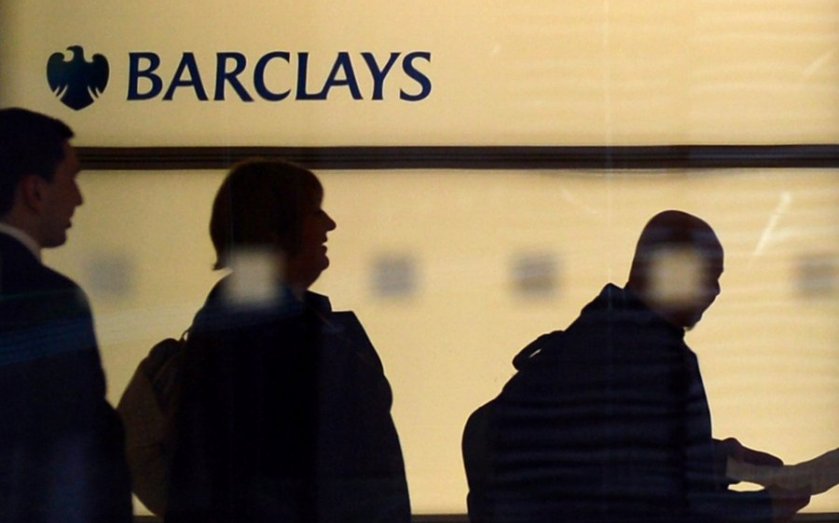 People walk past a Barclays logo at the