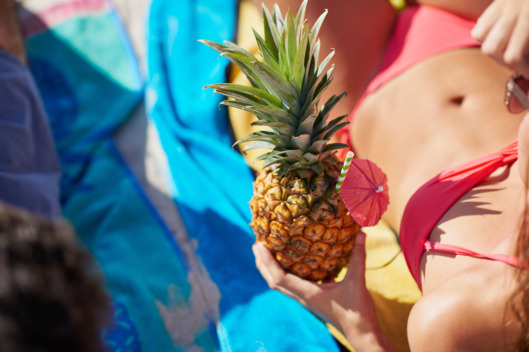 Woman holding pineapple with fit toned athletic tummy