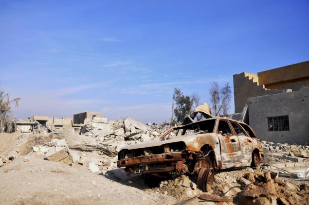 A burned out car lies amid damaged buildings in Ramadi after ISIS carried out suicide attacks