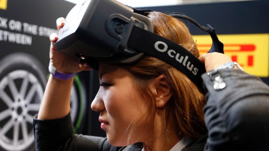 A woman puts on an Oculus virtual reality headset during preparations for the 2014 LA Auto Show in Los Angeles California