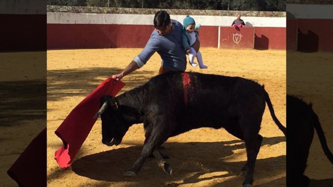 Bullfighter under fire for photo of him fighting a bull while holding baby daughter