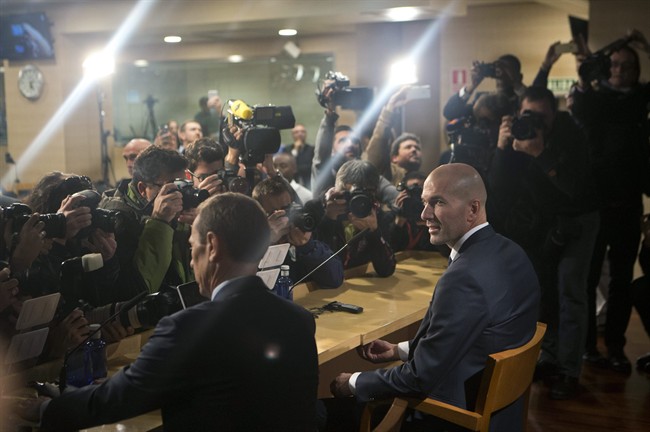 Real Madrid's newly appointed coach Zinedine Zidane right sits down in front of the media before his first press conference at the Santiago Bernabeu stadium in Madrid Spain Tuesday Jan. 5 2016. Real Madrid fired coach Rafael Benitez Monday after seve