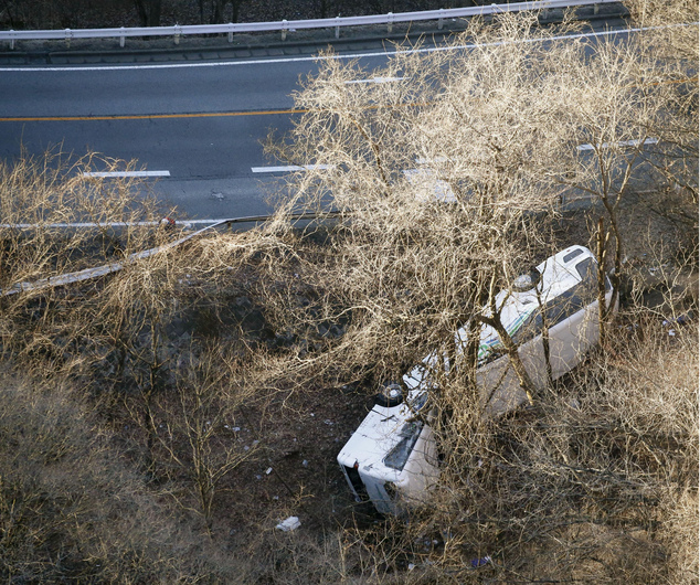 A bus lies after it veered off to the opposite lane on a mountain road in Karuizawa Nagano prefecture central Japan Friday Jan. 15 2016. Rescue officials