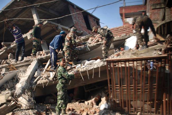 Indian soldiers and locals remove debris from a damaged building after an earthquake in Imphal capital of the northeastern Indian state of Manipur Monday Jan. 4 2016. A 6.7 magnitude earthquake hit India's remote northeast region before dawn on Mo