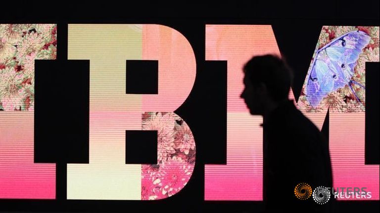 A man passes by an illuminated IBM logo at the CeBIT computer fair in Hanover