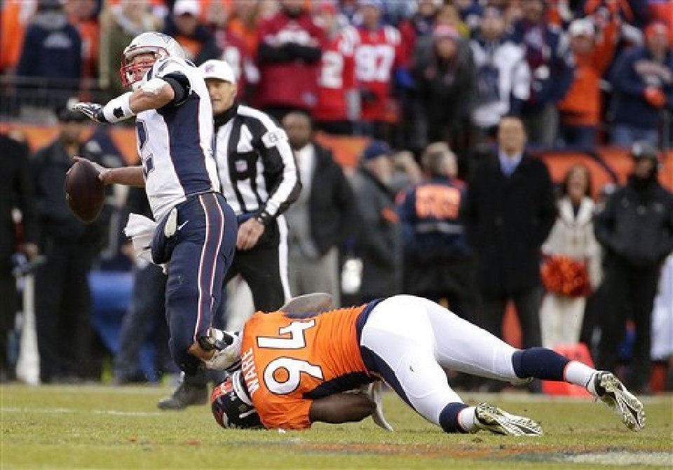 Patriots quarterback Tom Brady passes the ball as he is taken down by Denver Broncos outside linebacker De Marcus Ware during the second half of the AFC Championship game between the Denver Broncos and the New England Patriots Sunday