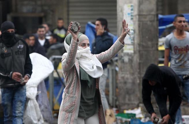 A young woman shows stones during clashes with Israeli forces in Hebr