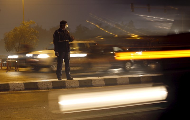 A traffic policeman wears a mask to protect himself from dust and air pollution as he signals to drivers in New Delhi