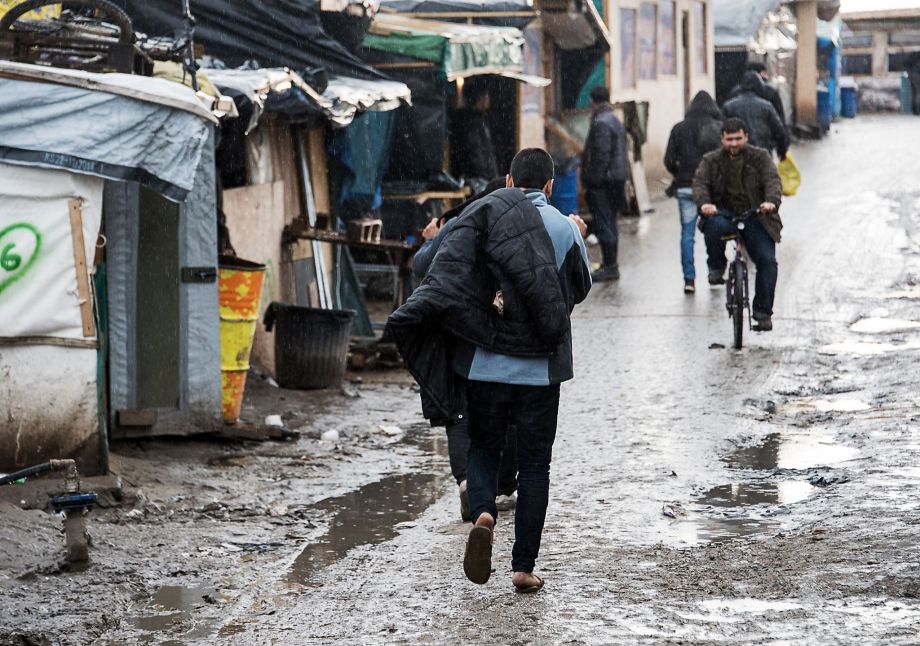 Refugees walk past makeshift sheds at the camp in Calais. Local authorities say 3,700 people are living there and between 800 and 1,000 would be affected by a court ordered eviction