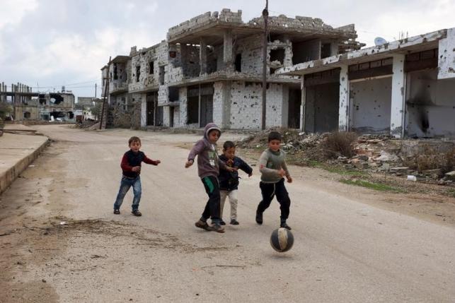 Children play near damaged buildings in the rebel held historic southern town of Bosra al-Sham Deraa Syria