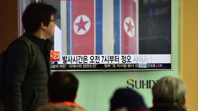 People watch a news report on North Korea's planned rocket launch as file footage from North Korea's 2012 launch of the Unha-3 rocket plays on a TV screen at a railway station in Seoul