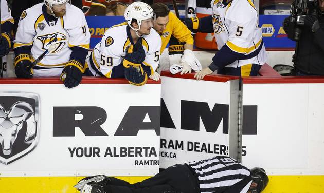 Nashville Predators&#039 players look over the bench at linesman Don Henderson after he was hit by Calgary Flames&#039 Dennis Wideman during second period NHL hockey action in Calgary Alberta Wednesday Jan. 27 2016. (Jeff McIntosh  The Canadian Press