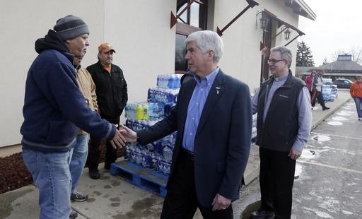 2016 Michigan Gov. Rick Snyder center and Our Lady of Guadalupe Church Deacon Omar Odette right meet with volunteers helping to load vehicles with bottled water in Flint Mich. Snyder